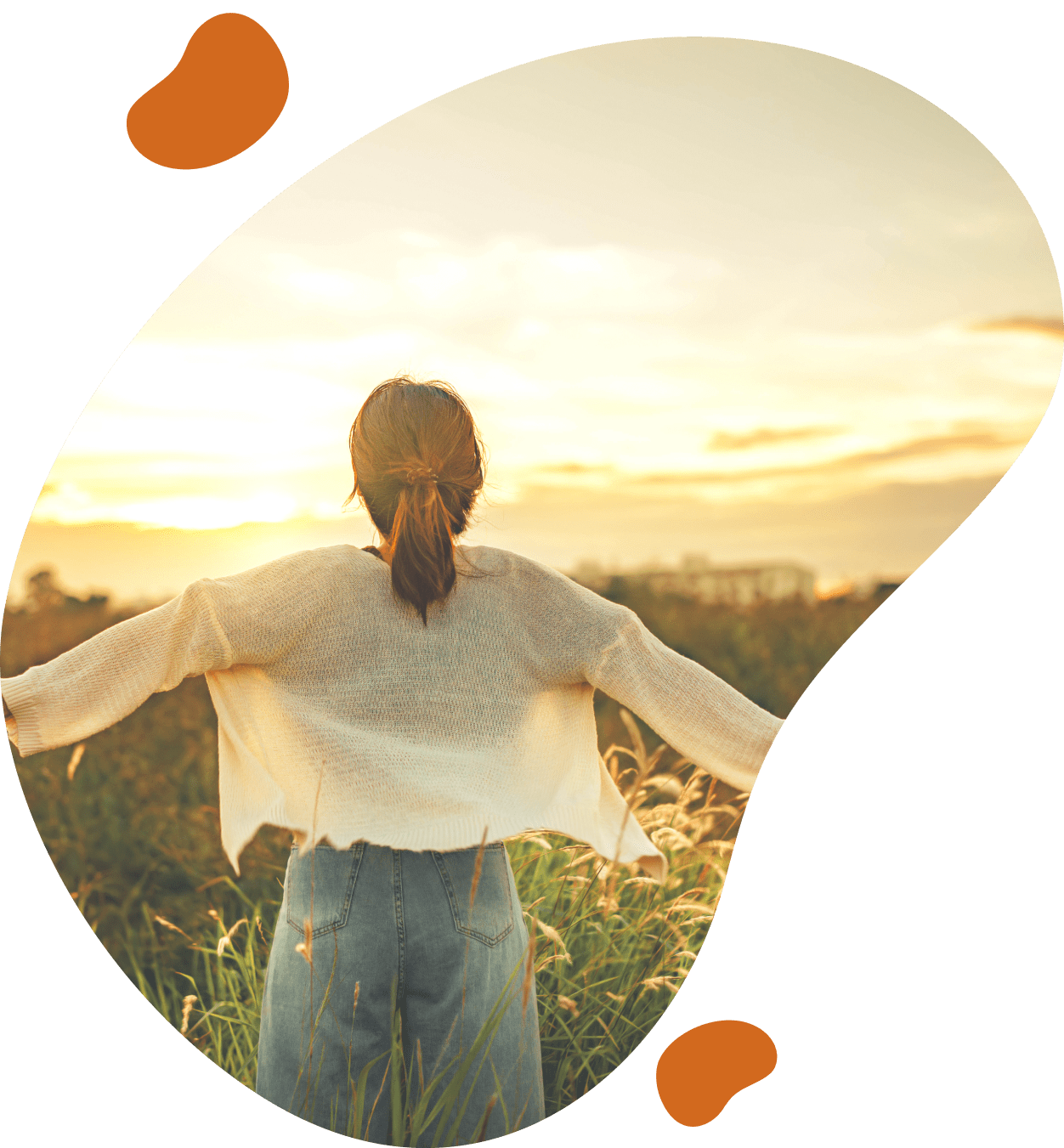 A person standing in the grass with arms outstretched.